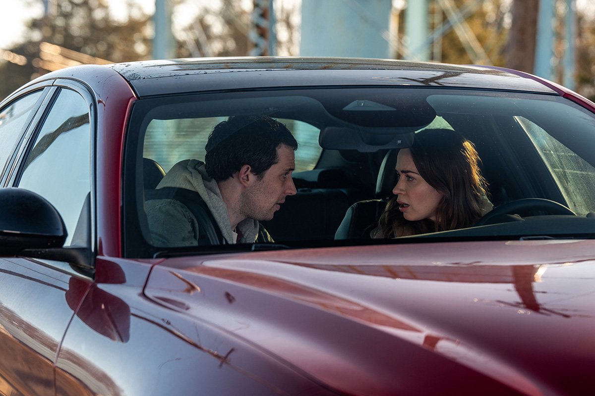 Josh O'Connor and Emily Blunt having a tense conversation inside a red car in a movie still from Disclosure Day.