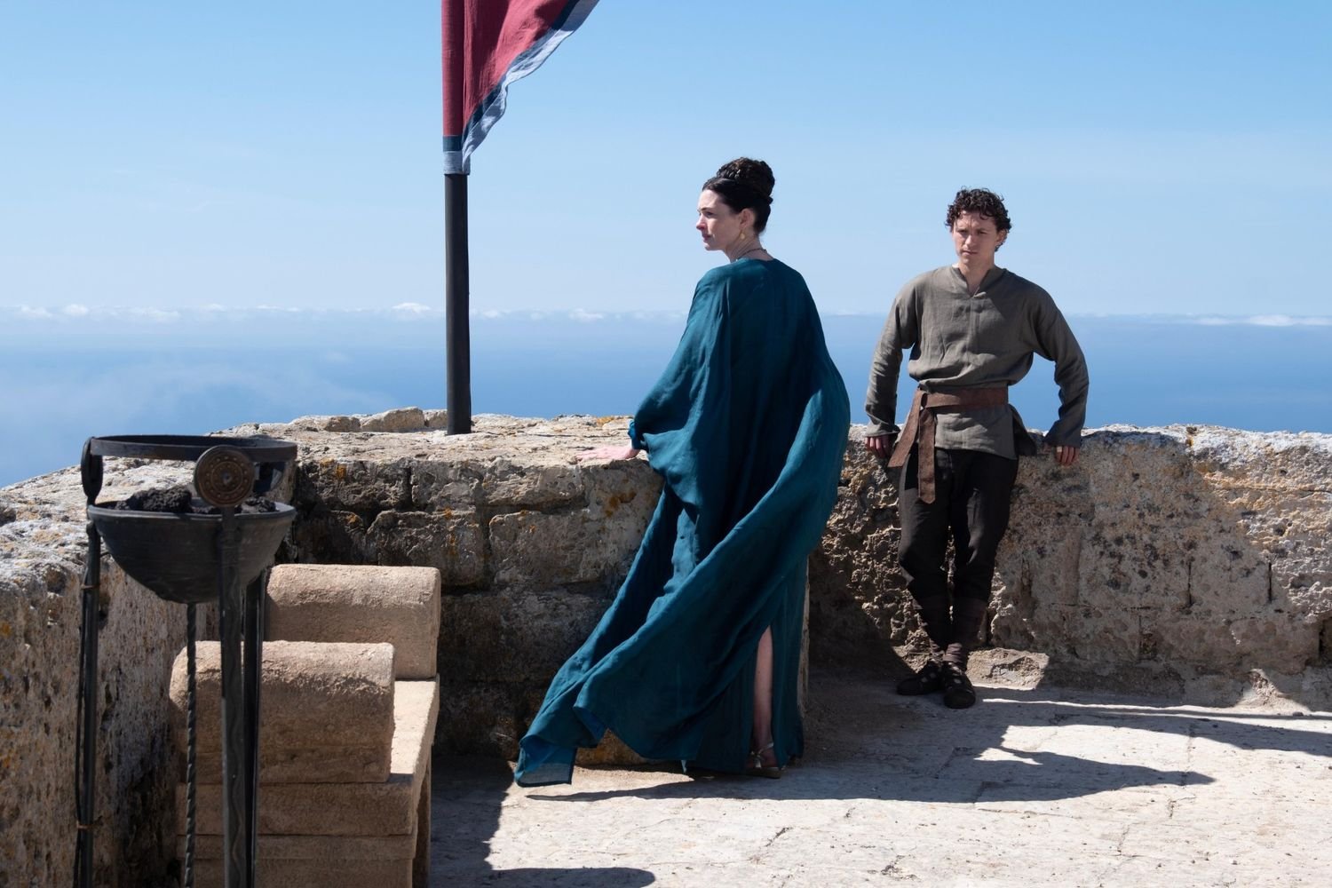 Anne Hathaway as Penelope in a blue gown with Tom Holland as her son Telemachus in Ithaca in Christopher Nolan's The Odyssey (2026)